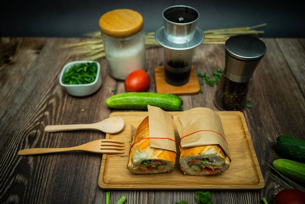 Snack at break time. Famous Vietnamese food is Banh mi thit and black coffee, popular street food from bread stuffed with raw material: pork, ham, pate, egg and fresh herbs.Typical Vietnamese sandwich - Fotoğraf, Görsel