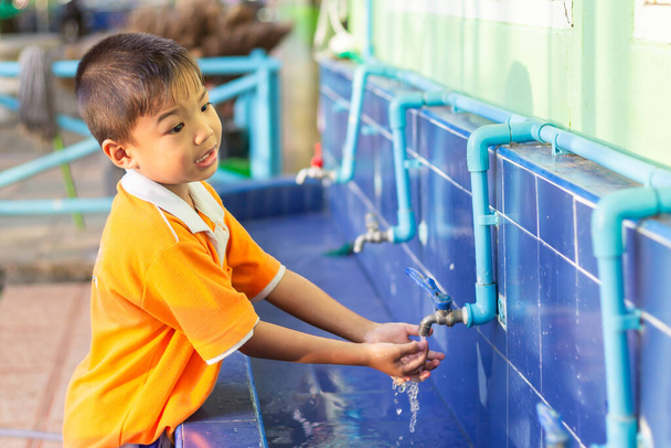 Menino asiático lavando as mãos antes de comer comida e depois jogar os brinquedos na tigela de lavagem na escola. Um rapaz de 5 anos. Saúde e conceito de criança. - Foto, Imagem