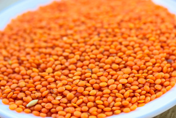 Red lentils in a round white plate: ingredients for a healthy diet natural meal - Photo, Image