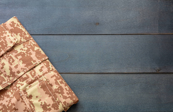 US army acu digital desert uniform shirt on blue wooden background. Military camouflage digital desert pattern folded shirt detail, copy space, template - Photo, Image