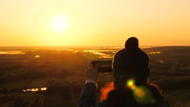 siluetti naisen auringonpaisteessa, selfie, ottaa kuvia auringonlaskun, auringonnousun. Ilmainen nuori tyttö turisti bloggaaja tallentaa selfie video päälle vuorten avulla älypuhelin kaunis maisema. - Materiaali, video