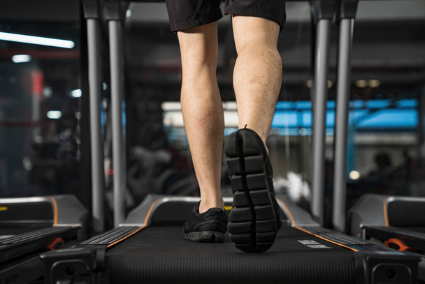 Primer plano de las piernas masculinas corriendo en la cinta de correr en el gimnasio, Entrenamiento de fitness deportivo, Concepto de personas de estilo de vida - Foto, Imagen