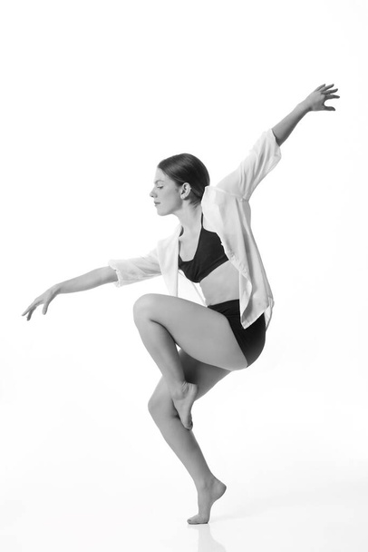 Stüdyo arka planında poz veren genç ve güzel bir dansçı. Siyah ve beyaz. İzole edilmiş - Fotoğraf, Görsel