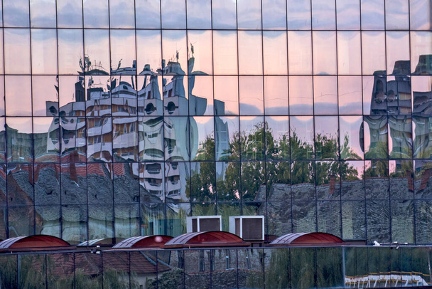 Een interessante avond abstracte beeld van de stad Zrenjanin door de reflectie in het glas gezien door de lens van de camera. - Foto, afbeelding