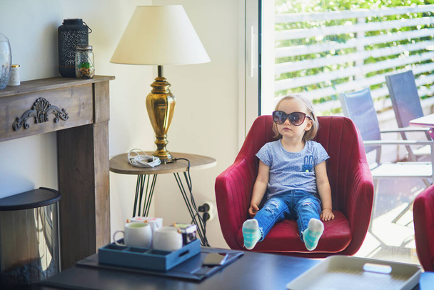 Adorable toddler girl wearing her mother's sunglasses and having fun at home - Foto, imagen