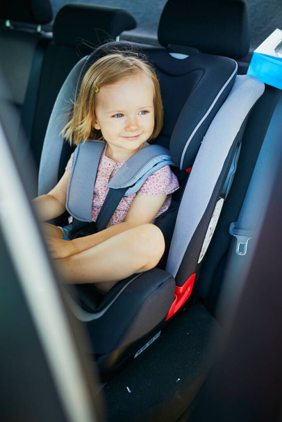 Adorable toddler girl in modern car seat. Little kid traveling by car. Child safety on the road. Trip with an infant. - Zdjęcie, obraz