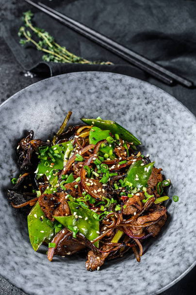 Wok. Soba stir fry noodles with beef and vegetables. Black background. Top view. - Photo, Image