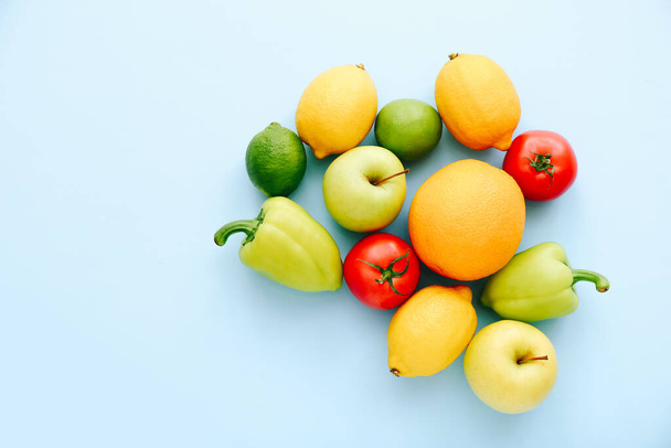 Różne świeże warzywa i owoce na niebieskim tle. Koncepcja zakupów. Pomidor, pieprz, cytryna, jabłko i limonka. Widok z góry - Zdjęcie, obraz
