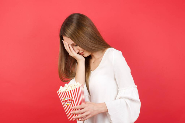 crying woman in studio holding pop corn box - Valokuva, kuva