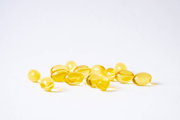 黄色魚油サプリメントカプセルの選択的な焦点は、白い背景を分離します。良い体の栄養のための薬とビタミン。医療・医療の概念. - 写真・画像