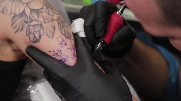 Tetováló művész csinál egy tetoválás egy fiatal lány kar. - Felvétel, videó