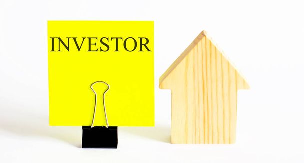 Table with wooden houses with the word INVESTOR . The concept of rental housing. Rent an apartment or house. Payment for rent. - Фото, изображение