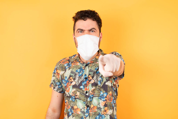 handsome young man with protective mask  pointing displeased and frustrated to the camera, angry and furious ready to fight with you. - Photo, Image