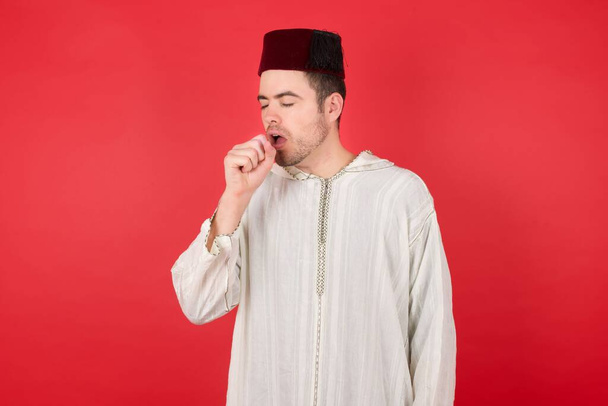 joven guapo usando sombrero turco tradicional fez sensación de malestar y tos como síntoma de frío o bronquitis. Concepto sanitario. - Foto, imagen