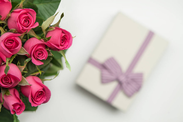 Букет з рожевих троянд з подарунками на столі
. - Фото, зображення