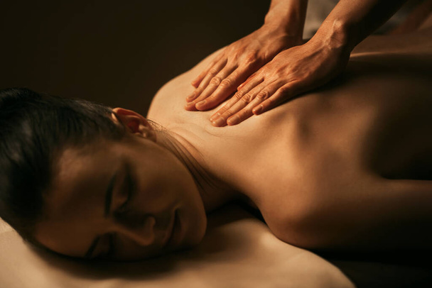 The beautiful girl has massage. Authentic image of luxury spa treatment. Warm colors, charming light. - Foto, afbeelding