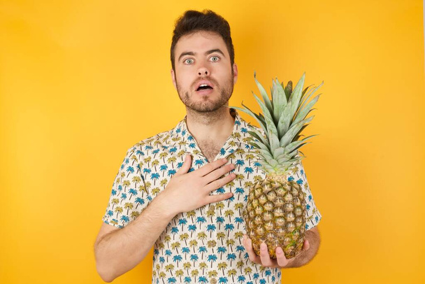 Egy fiatal ember ananásszal, aki zavarban van, hogy észrevegyen valami furcsát. Emberek, csend reakció és érzelmek. - Fotó, kép