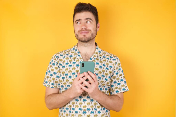 handsome young man posing with smartphone on color studio background - Φωτογραφία, εικόνα