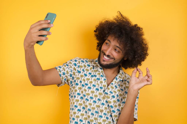 Foto von charmantem Mann in rotem Hemd, lächelnd und mit einem Selfie bereit, es in ihren sozialen Medien zu posten. - Foto, Bild