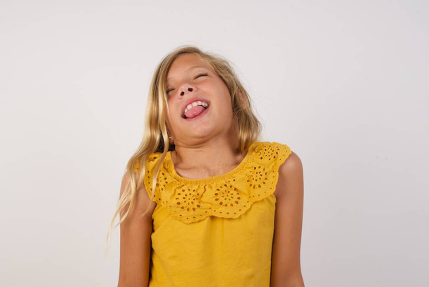 Nettes kleines Mädchen streckt die Zunge glücklich mit lustigem Ausdruck heraus. Emotionales Konzept. - Foto, Bild