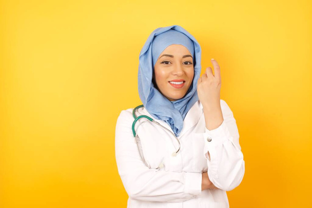 Jeune femme médecin portant un uniforme médical signe venir ici geste avec la main invitant accueillant heureux et souriant - Photo, image