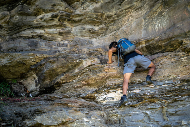 Young boy climbing the rocks wearing a backpack. - Fotografie, Obrázek
