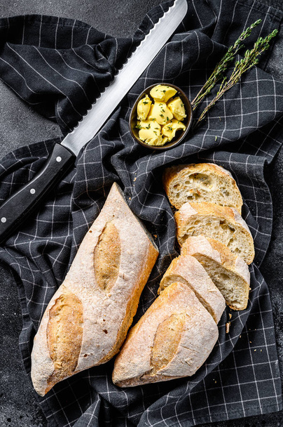 Artisanal baguettes and cut slice with butter. black background. top view. - Photo, Image