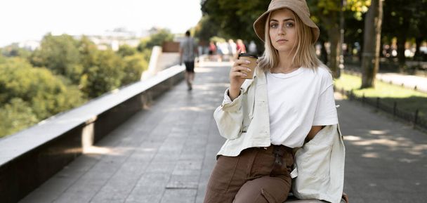 donna turistica in una città europea, turismo in Europa. giovane donna nel parco con il caffè in mano. Tazza di carta usa e getta. - Foto, immagini