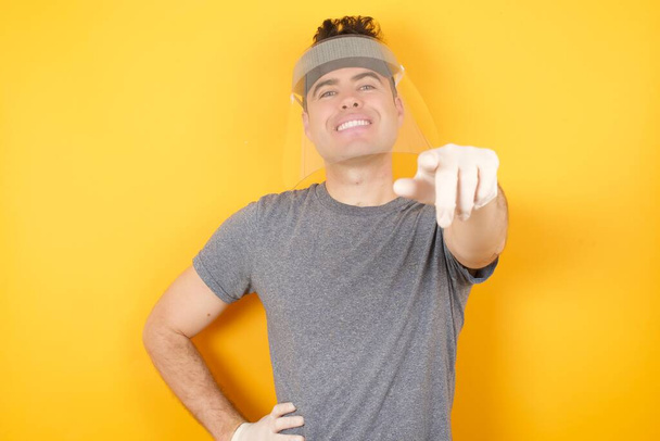 boldog mosolygós férfi műanyag védősapkában, ujjal mutogatva a kamerára  - Fotó, kép