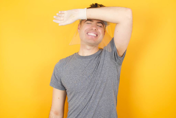 άνδρας σε πλαστικό προστατευτικό καπέλο, που καλύπτει τα μάτια με το χέρι χαμογελώντας χαρούμενα και αστεία  - Φωτογραφία, εικόνα