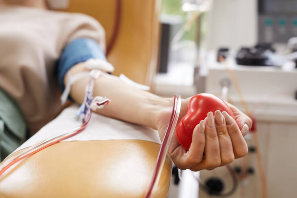 Detailní záběr pacienta s trubicemi v ruce mačkat míč v ruce při darování krve - Fotografie, Obrázek