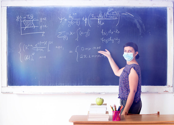 Teacher with mask teaching math lesson at school. Social distanting and classroom safety during coronavirus epidemic - Photo, image