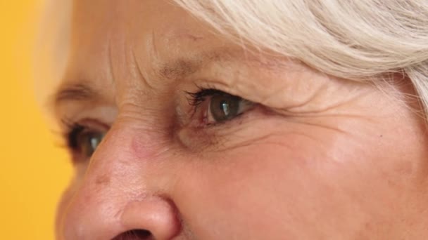 Yeşil gözlü, yaşlı bir kadının kırışıklıklarıyla dolu bir makro fotoğraf. Yan görünüm - Video, Çekim