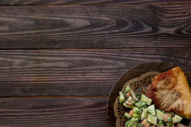 τηγανητό χοιρινό με σαλάτα λαχανικών ντομάτας και αγγούρια με μαγιονέζα σε ξύλινο τραπέζι σε χρώμα wenge. Υψηλής ποιότητας φωτογραφία - Φωτογραφία, εικόνα