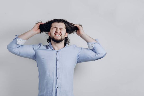 um homem de sucesso está com raiva e rasga seu cabelo longo.  - Foto, Imagem