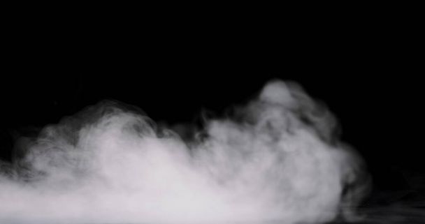 füstfelhő gördül keresztül a padlón egy fekete háttér. - Fotó, kép