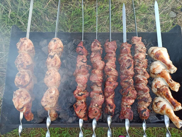 Grilled kebab cooking on metal skewer. Roasted meat cooked at barbecue. BBQ fresh beef meat chop slices. Traditional eastern dish, shish kebab. Grill on charcoal and flame, picnic, street food - Photo, Image