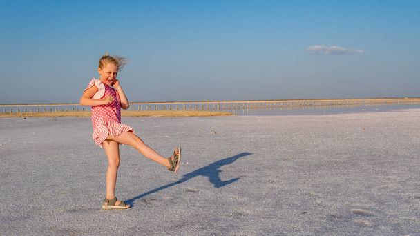 Cheerful lady in a beautiful dress, an adult with a kind look on a salty background like in winter on a lake, blue clouds during the day and in summer - Photo, Image