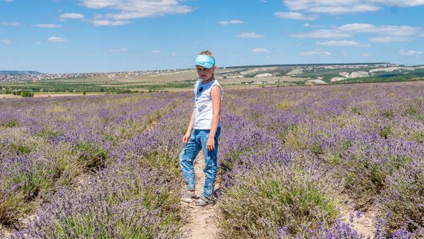 Joyful in a lavender field with a kind look sunglasses having cheerful with a charming smile stands - Фото, изображение