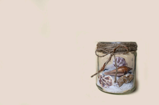 pot en verre avec sel de mer et coquillages sur un fond sablonneux - Photo, image
