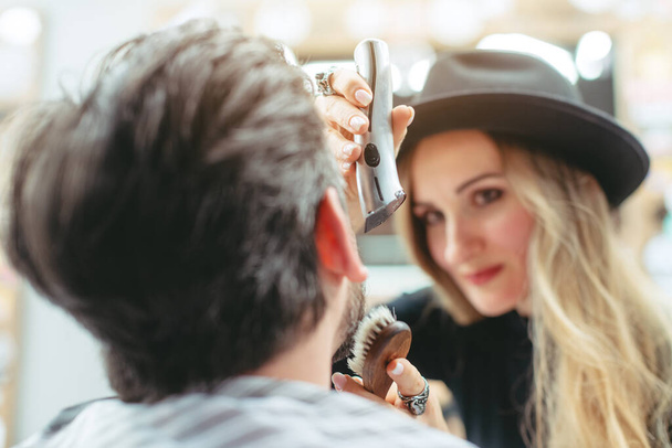 Kobieta fryzjer cięcie i przycinanie brody klienta w jej sklepie - Zdjęcie, obraz