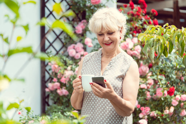 Vanhempi nainen tai isoäiti käyttää puhelinta tekstaamaan perheelleen - Valokuva, kuva