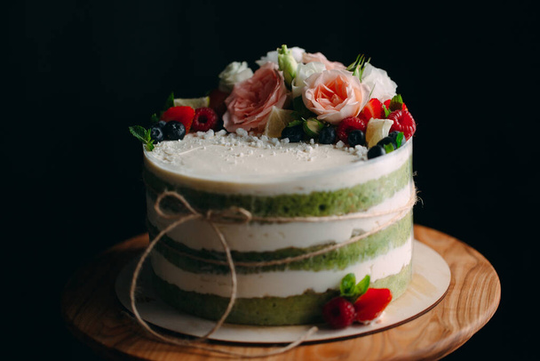 Cake is decorated with flowers on a dark background. - Φωτογραφία, εικόνα