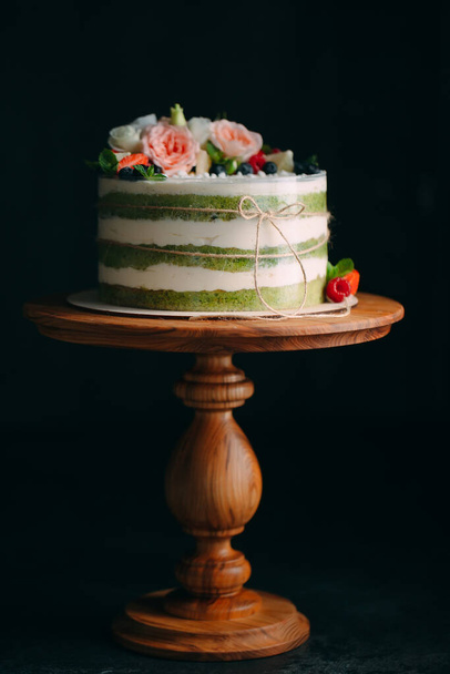 Cake is decorated with flowers on a dark background. - Фото, изображение