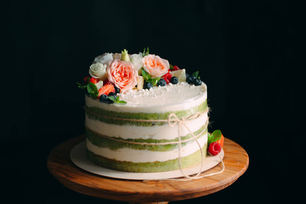 Cake is decorated with flowers on a dark background. - Foto, imagen