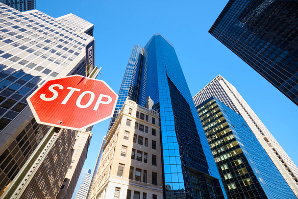 Взгляд вверх на знак остановки на одной из улиц Нью-Йорка с современными зданиями на заднем плане, выборочный фокус, США. - Фото, изображение