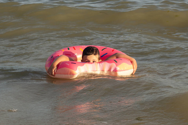 Ragazzo di 5 anni si bagna in mare in un anello di vita in una giornata di sole - Foto, immagini