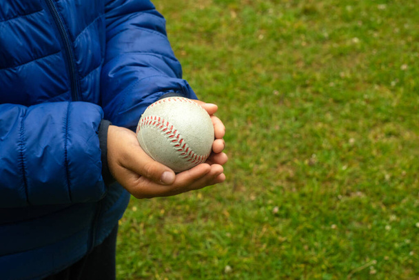 Las manos de los niños sostienen una pelota de béisbol - Foto, imagen