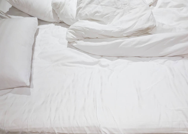 Yatak odasındaki dağınık yatak, beyaz yastıklar, dağınık çarşaf ve battaniye, rahat ve rahat yatak odası. - Fotoğraf, Görsel