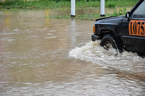 Kerekek és pickup teherautók haladtak el az úton, amely tele volt az árvíz az esős időben, koncepció a biztosítási és biztonsági. - Fotó, kép
